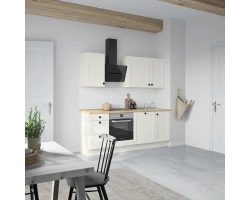 Cuisine claire avec armoires blanches, hotte aspirante et plan de travail en bois.