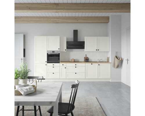 Cuisine claire avec armoires blanches, hotte aspirante et plans de travail en bois.