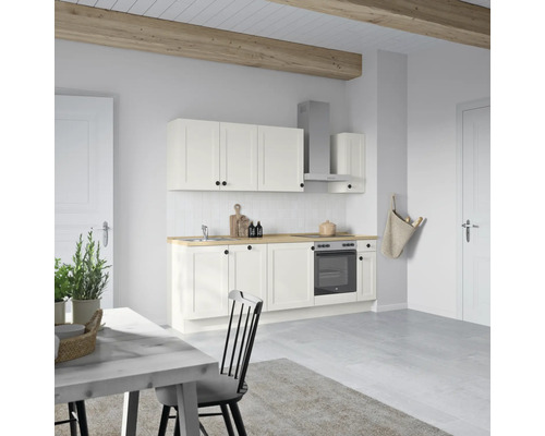 Cuisine claire avec armoires blanches, plan de travail en bois et table à manger