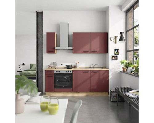 Cuisine moderne avec des armoires rouges, une hotte aspirante et une cuisinière électrique dans une pièce lumineuse.