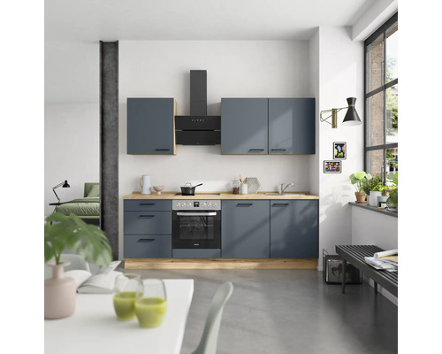 Cuisine moderne avec armoires bleues, hotte aspirante et plan de travail en bois dans une pièce lumineuse.