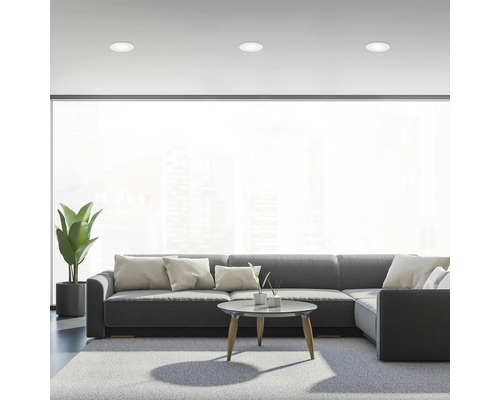 Salon avec canapé gris, tapis et spots encastrés pour une ambiance lumineuse