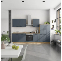 Cuisine moderne avec armoires bleues, plans de travail en bois et hotte en acier inoxydable dans une pièce lumineuse.