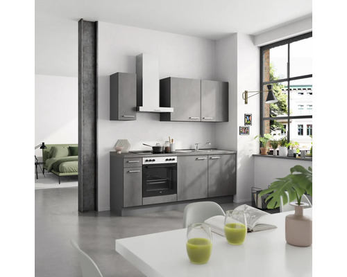 Cuisine moderne avec armoires grises, cuisinière, hotte aspirante et table à manger dans une pièce lumineuse.