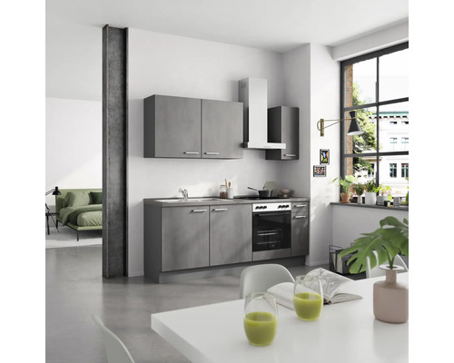 Cuisine avec armoires de cuisine, évier, cuisinière, hotte aspirante et table à manger dans une pièce lumineuse.