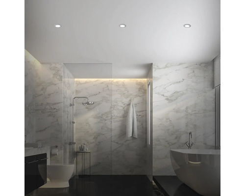 Salle de bain lumineuse avec douche, baignoire, toilettes et carreaux de marbre.