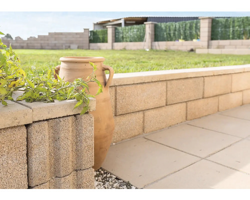 Muret de jardin en blocs de béton avec amphore décorative et plantes