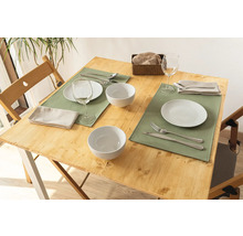 Gedeckter Holztisch mit Tellern, Schüsseln, Gläsern, Besteck und Servietten