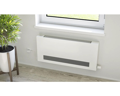 Flacher Heizkörper an einer Wand in einem hellen Raum neben einer Zimmerpflanze unter einem Fenster