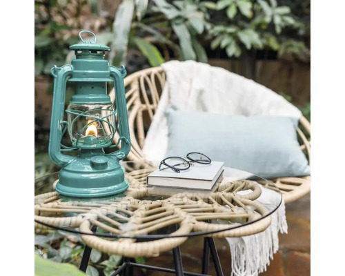 Dekorative Petroleumlampe auf einem Gartentisch neben einem Sessel.
