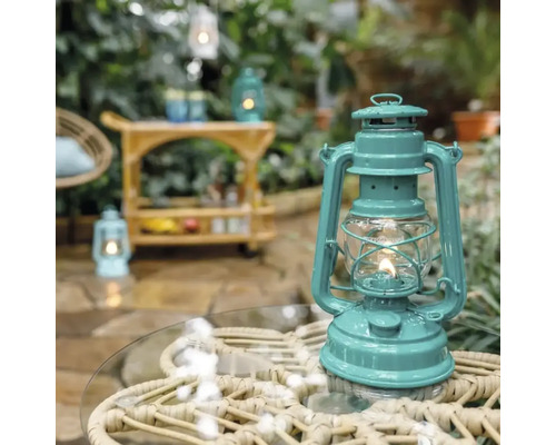 Dekorative Petroleumlampe auf Gartentisch mit Barwagen im Hintergrund