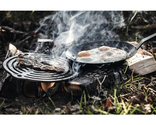 Zubereitung von Speck und Eiern über einem Lagerfeuer.