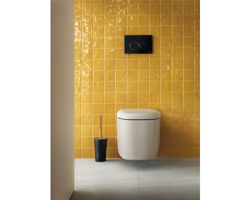 Modernes Badezimmer mit wandhängendem WC, Betätigungsplatte und WC-Bürstengarnitur vor einer gefliesten Wand