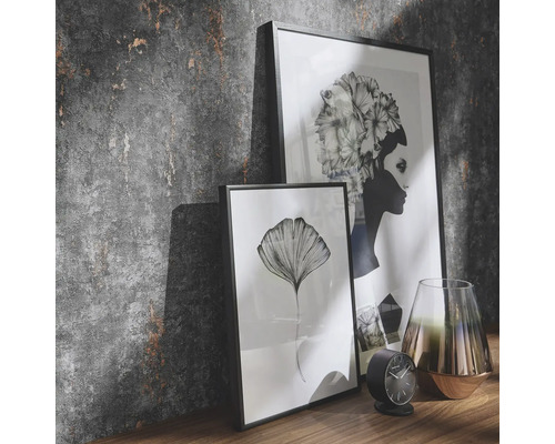 Dekorative Szene mit zwei gerahmten Bildern, einer Uhr und einer Vase auf einem Regal vor einer strukturierten Wand.