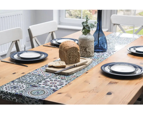 Table à manger dressée avec chemin de table, vaisselle, vases et pain