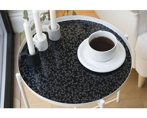 Table avec motif floral, bougies et tasse de café.