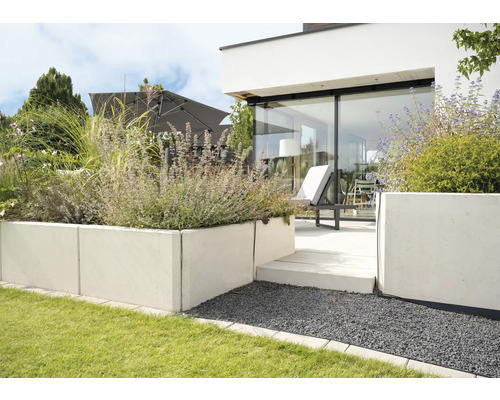 Garten mit Betonmauern, Pflanzen und Terrasse mit Liegestuhl