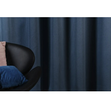 Rideau bleu décoratif à côté d''un fauteuil noir avec des coussins