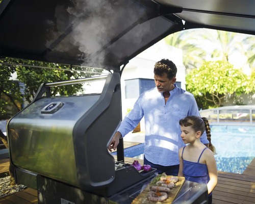 Vater und Tochter grillen Würstchen auf einem Gasgrill im Freien