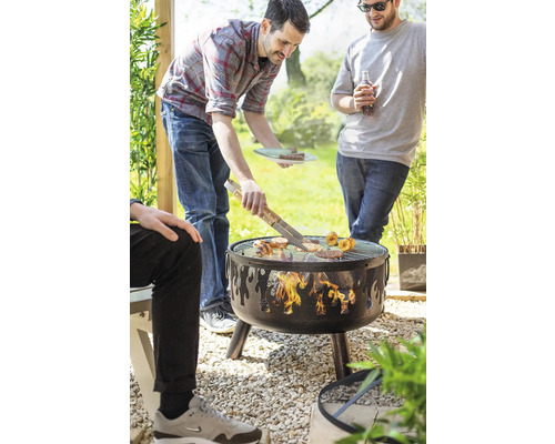 Des personnes font des grillades sur un barbecue à charbon de bois dans le jardin.