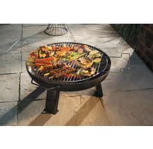 Grill rond avec des aliments grillés tels que viande, légumes et brochettes sur un sol en pierre
