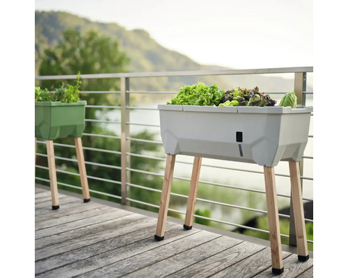 Zwei Hochbeete aus Kunststoff mit Holzbeinen auf einer Holzterrasse mit Blick auf einen See