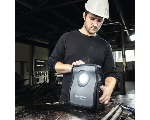 Ein Arbeiter mit Schutzhelm bedient eine Scangrip Arbeitsleuchte.