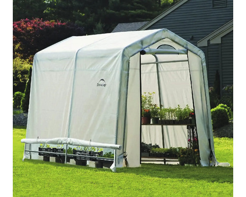 Gewächshaus mit Pflanzenregalen auf einer Rasenfläche