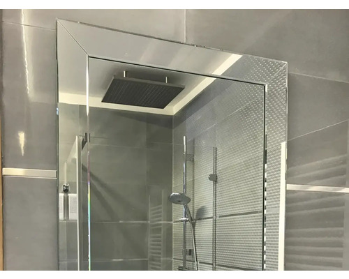 Cabine de douche avec pommeau de douche et robinetterie dans une salle de bains avec des carreaux gris