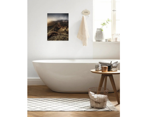 Badezimmer mit Badewanne, Hocker, Teppich und Wandbild mit Landschaftsmotiv