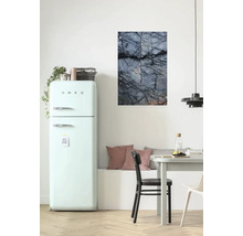 Wohnraum mit Kühlschrank, Esstisch und einem Wandbild mit Steinmotiv.