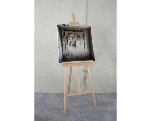Une boîte en bois avec une vieille porte à l''intérieur est posée sur un chevalet en bois.