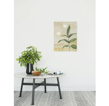 Dekoratives Zimmer mit einem runden Tisch, einer Vase mit Blumen, einer Schale und einem gerahmten Pflanzenbild an der Wand.