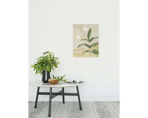 Dekoratives Zimmer mit einem runden Tisch, einer Vase mit Blumen, einer Schale und einem gerahmten Pflanzenbild an der Wand.