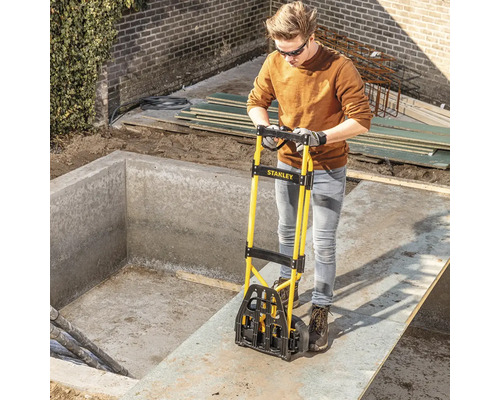 Une personne utilise un monte-escalier Stanley pour transporter des matériaux de construction sur un chantier.