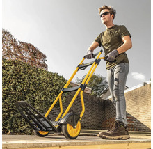 Homme poussant un diable jaune et noir de Stanley dans le jardin.