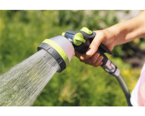 Hand hält Gartenschlauch-Sprühkopf mit Wasserstrahl