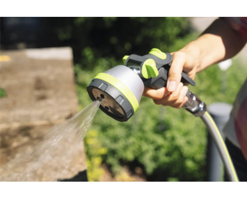 Hand hält Gartenschlauch-Spritzpistole mit Wasserstrahl.