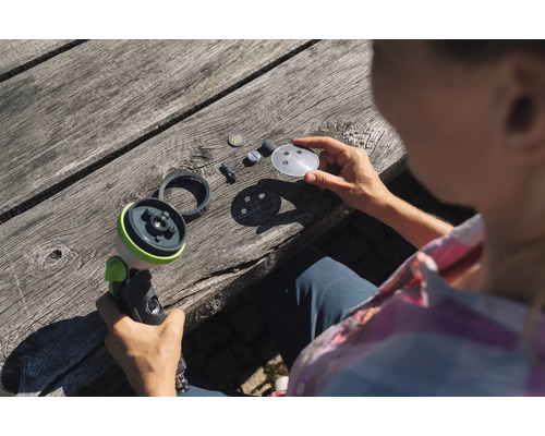 Frau demontiert Gartenspritze auf Holztisch