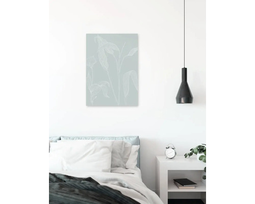 Chambre avec lit, table de chevet, lampe et tableau mural avec motif végétal