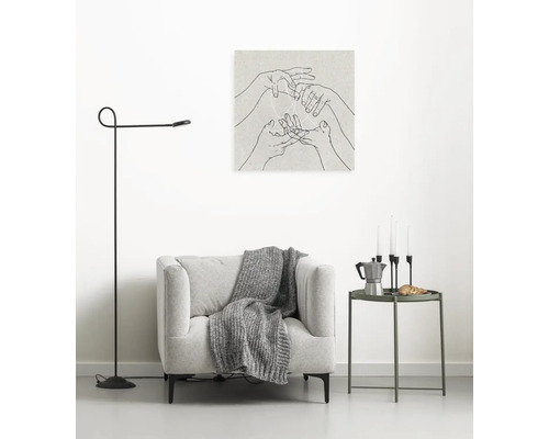 Scène de salon avec fauteuil, lampadaire, table d''appoint et décoration murale avec des mains