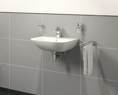 Keramikwaschbecken mit Armatur, Seifenspender und Handtuchhalter an einer gefliesten Wand