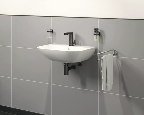 Lavabo mural avec robinet, distributeur de savon, gobelet à brosse à dents et porte-serviettes dans la salle de bains.