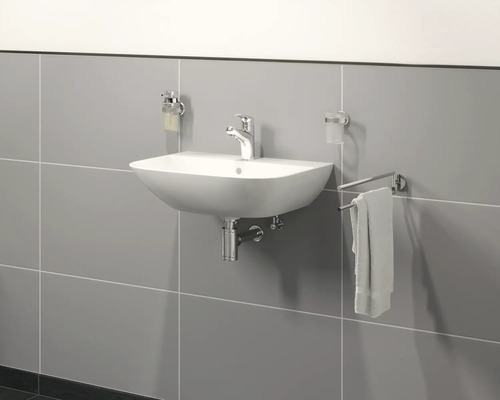 Keramikwaschbecken mit Armatur, Seifenspender, Zahnputzbecher und Handtuchhalter an einer grauen Wand