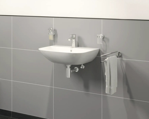 Wandmontiertes Waschbecken mit Armatur, Seifenspender, Zahnputzbecher und Handtuchhalter an grauer Wand