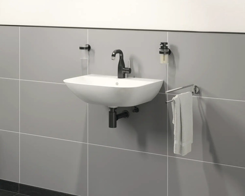 Wandmontiertes Waschbecken mit Armatur, Seifenspender und Handtuchhalter vor gefliester Wand