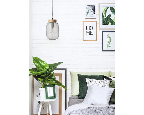 Dekoratives Schlafzimmer mit Lampe, Zimmerpflanze, Kissen und Bildern an der Wand.