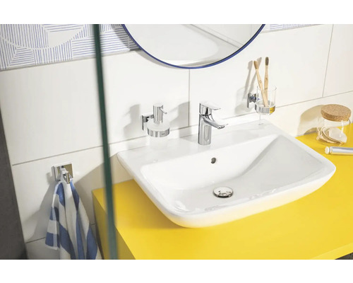 Helles Badezimmer mit Waschbecken, Armatur, Seifenspender, Zahnputzbecher und Handtuchhalter