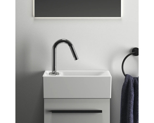 Waschtisch mit Armatur, Handtuch und Spiegel im Badezimmer