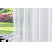 Voilage blanc devant une fenêtre avec vue sur le jardin